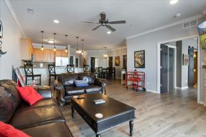 a living room with leather couches and a table at Lands End Condo with Amazing Main Channel Views, 2 Pools, Playground & Boat Slip in Laguna Beach
