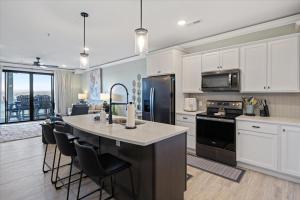 a kitchen with white cabinets and a kitchen island with black appliances at Newly Designed Topsider Condo w/ Beautiful Main Channel Views in Laguna Beach