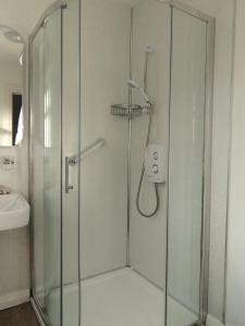 une douche en verre dans une salle de bain avec un lavabo dans l'établissement Knightstown Cottage, à Île de Valentia