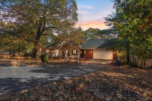 a house with a driveway and a garage at Six Suites with Hot Tubs, Private Jacuzzi Baths, Wooded Garden and Lake Access with Boat Slip in Damsel