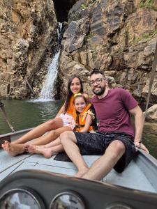 a man and woman and a child sitting in a boat in front of a waterfall at MesaVibes in Colinas Do Sul