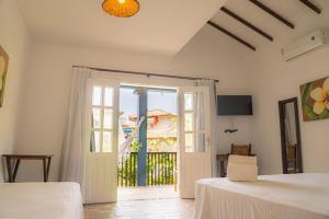 a bedroom with two beds and a door to a balcony at Hotel Espelho D'Água Arraial e Beach Club in Arraial d'Ajuda
