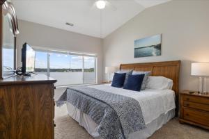 a bedroom with a bed with blue pillows and a window at Main Channel Views, Screened Porch, Pool & Boat Slip in Lake Ozark +67 photos