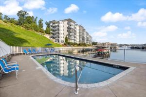 a swimming pool with chairs and a building and water at Main Channel Views, Screened Porch, Pool & Boat Slip in Lake Ozark