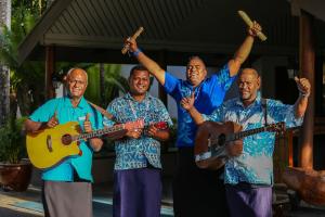 a group of four men holding up their instruments at Fiji Hideaway Resort & Spa in Tangangge