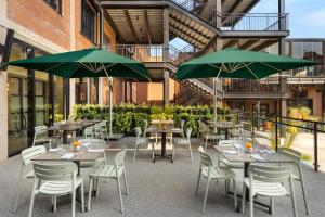 un patio avec des tables et des chaises et des parasols verts dans l'établissement Hard Rock Hotel London Ontario, à London
