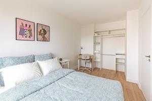 a white bedroom with a blue bed and a desk at Friendly and spacious apartment in Créteil ! in Créteil