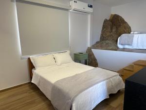 um quarto com uma cama branca e uma janela em Loft MarSol em Piúma