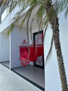 uma rede pendurada num edifício ao lado de uma palmeira em Loft MarSol em Piúma