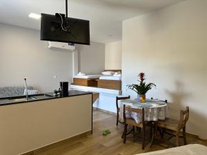 a kitchen and dining room with a table and a bed at Loft MarSol in Piúma