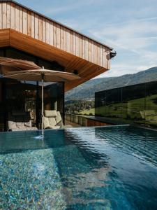 a house with a swimming pool with an umbrella at Lärchenlodge SkySpa and Rooftop Pool inklusive Stubai SuperCard in Fulpmes