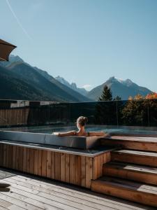a person sitting in a bath tub on a deck at Lärchenlodge SkySpa and Rooftop Pool inklusive Stubai SuperCard in Fulpmes