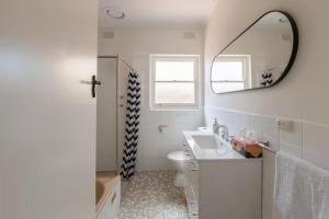 a white bathroom with a sink and a mirror at Gem Apartment 4 - Courtyard I Beach I Wifi I Cafes in Glenelg