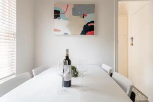 a white dining room with a white table with two wine glasses at Gem Apartment 4 - Courtyard I Beach I Wifi I Cafes in Glenelg +11 photos