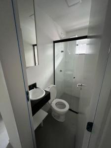 a white bathroom with a toilet and a sink at Studio47 - Compact, equipped and well located in Itajaí