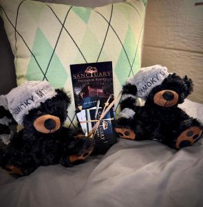 two teddy bears sitting on a bed with a book at "The 19th Hole" Luxury Treehouse w Golf Views & Private 20ft Slide - 10 Miles from Dollywood in Catlettsburg
