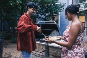 a man and a woman cooking food on a grill at Centrally-Located 1BR Suite with Resort Pool View in Frisco