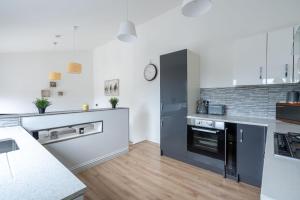 a kitchen with white and black appliances and wooden floors at Fife coastal corner in Buckhaven