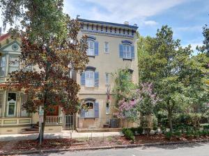 a large house with blue windows and trees in front at Charm on Liberty in Savannah