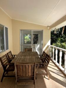 een houten tafel en stoelen op een veranda bij Maree's Beachfront House - Free Internet in Arorangi
