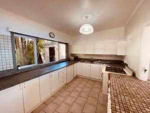 een grote keuken met witte kasten en een raam bij Maree's Beachfront House - Free Internet in Arorangi