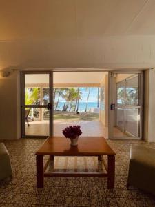 een woonkamer met een tafel en uitzicht op de oceaan bij Maree's Beachfront House - Free Internet in Arorangi +7 foto's