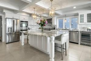 een keuken met een groot wit kookeiland met een vaas met bloemen bij Sunrise to Sunset Waterfront Retreat in Milford