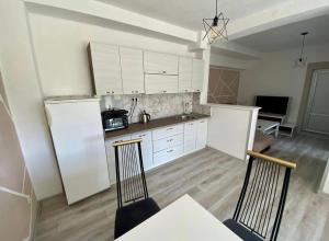 una cucina con mobili bianchi, tavolo e sedie di Villa Lilak a Bihać