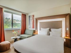 a hotel room with a large bed and a chair at Novotel Lyon Centre-Confluence Bord de Saone in Lyon
