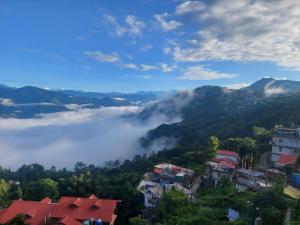 Blick auf eine Stadt in den Bergen mit Wolken in der Unterkunft Mala cottage in Kalimpong