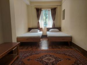 zwei Betten in einem Zimmer mit Fenster in der Unterkunft Mala cottage in Kalimpong