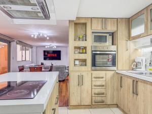 una cucina con mobili in legno e un soggiorno di Emerald Retreat con Jacuzzi y BBQ a Cuenca