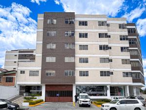 un edificio alto con auto parcheggiate in un parcheggio di Emerald Retreat con Jacuzzi y BBQ a Cuenca