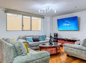 un soggiorno con due divani e una TV di Emerald Retreat con Jacuzzi y BBQ a Cuenca