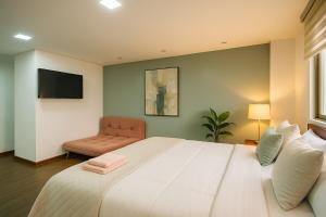 una camera da letto con un grande letto bianco e una sedia di Emerald Retreat con Jacuzzi y BBQ a Cuenca