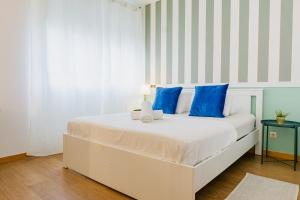 1 cama blanca con almohadas azules en una habitación en Quartos da Expo, en Lisboa 58 fotos más