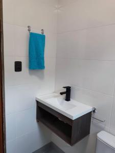 a bathroom with a white sink and a blue towel at Apartamento de 2 Quartos para 4 Pessoas - 5 min da Praia in Garopaba