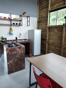 a kitchen with a table and a refrigerator at Apartamento de 2 Quartos para 4 Pessoas - 5 min da Praia in Garopaba