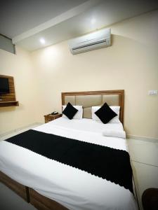 a bedroom with a large white bed with black pillows at Hotel SK GRAND in Sohāna