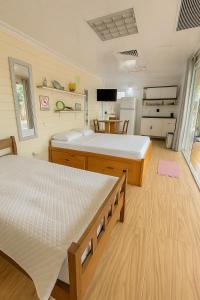 a bedroom with two beds and a kitchen at Casa do bananal - Praia Estaleiro (Ubatumirim) -Ubatuba/SP in Ubatuba