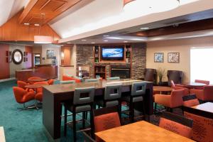 Un restaurante con mesas y sillas y un televisor de pantalla plana. en Residence Inn by Marriott Rogers, en Rogers