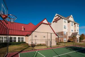 una pista de tenis frente a una casa con un aro de baloncesto en Residence Inn by Marriott Rogers, en Rogers
