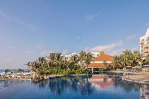 a resort swimming pool with palm trees and buildings at Fiesta Americana Condesa Cancun - All Inclusive in Cancún