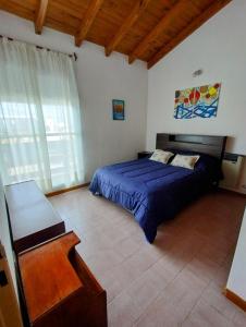 a bedroom with a bed with a blue comforter at CASA AGUAS AZULES 6 pax LAS GRUTAS in Las Grutas