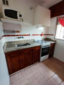 a kitchen with a sink and a stove and a microwave at CASA AGUAS AZULES 6 pax LAS GRUTAS in Las Grutas