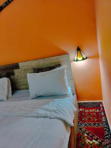 une chambre avec un lit avec un mur orange dans l'établissement Akwaba lodge, à Sale
