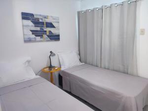 two beds in a small room with a window at STUDIO URBANO Ar Garagem 2 Quartos in Petrolina