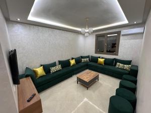 a living room with a green couch and yellow pillows at Résidence Saadia, Khouribga in Khouribga +6 photos