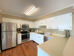 a kitchen with white cabinets and a stainless steel refrigerator at Gone Fishin' in Edisto Island +29 photos