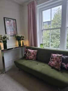 a green couch in a living room with a window at Boutique Accommodation in London